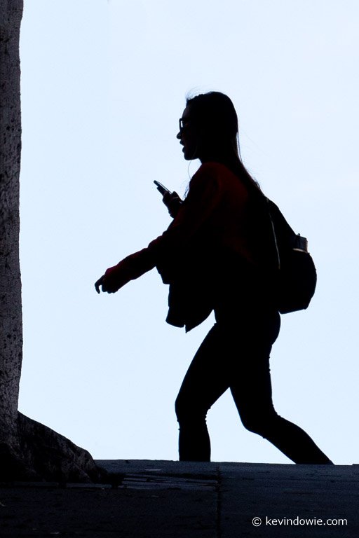 young woman silhouetted crossing the street